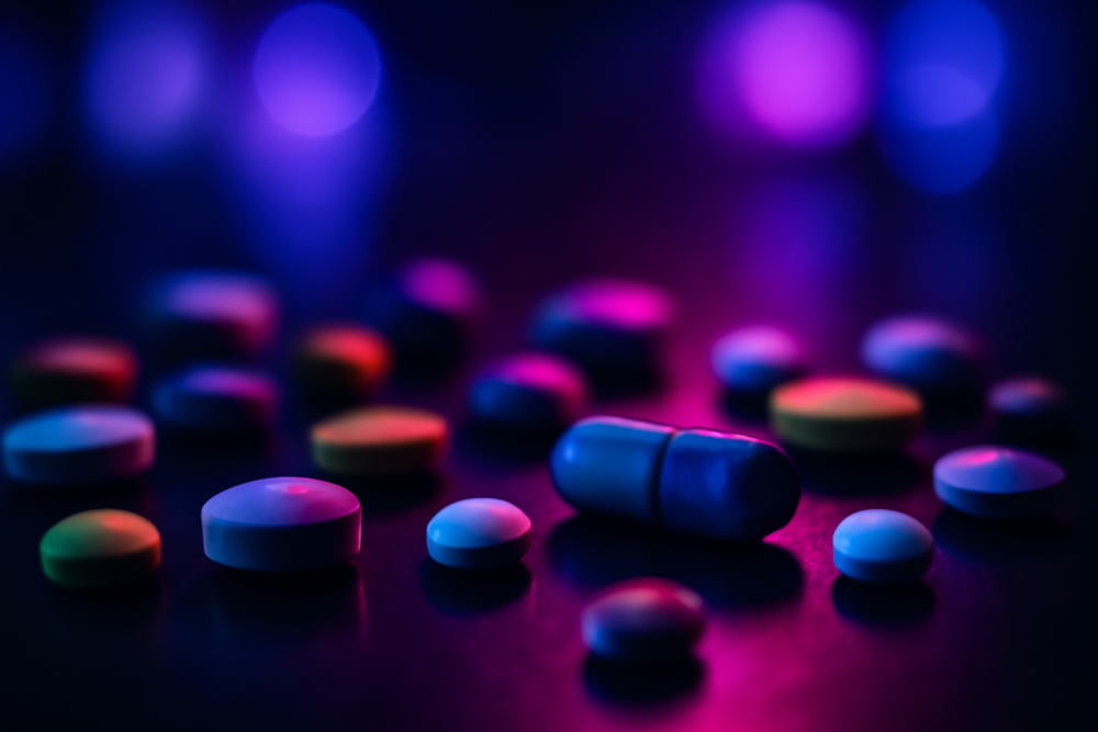 Kleurrijke pillen op donkere ondergrond als symbool voor MDMA en XTC gebruik